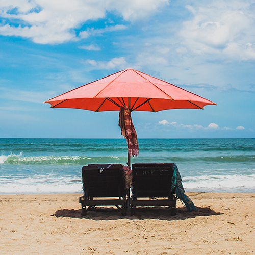 Deux chaises longues sous un parasol sur une plage de sable doré