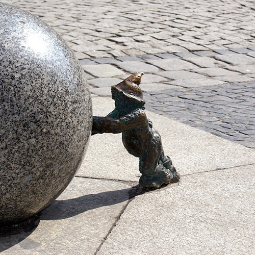 Nain en bronze poussant une grosse boule 